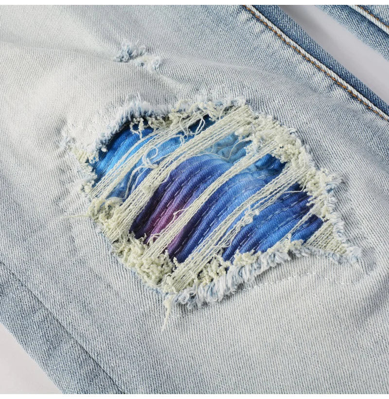 Detailed close-up of the blue patchwork and frayed edges on the Nofacebaby M5 Jeans’ ripped sections.