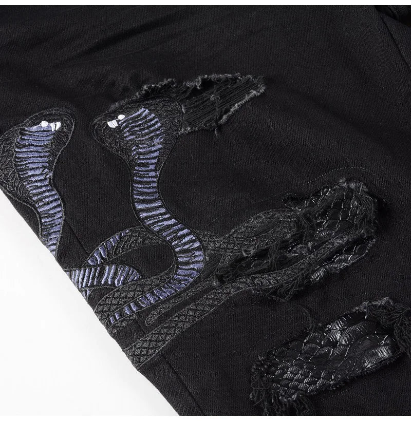Close-up of the Nofacebaby Snake Jeans' intricate snake print detailing along the leg, set against distressed black denim.