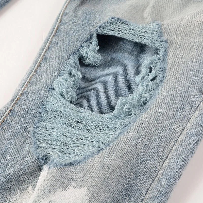 Detailed view of distressed Nofacebaby Vitto jeans with Swarovski crystal embellishments within tears.
